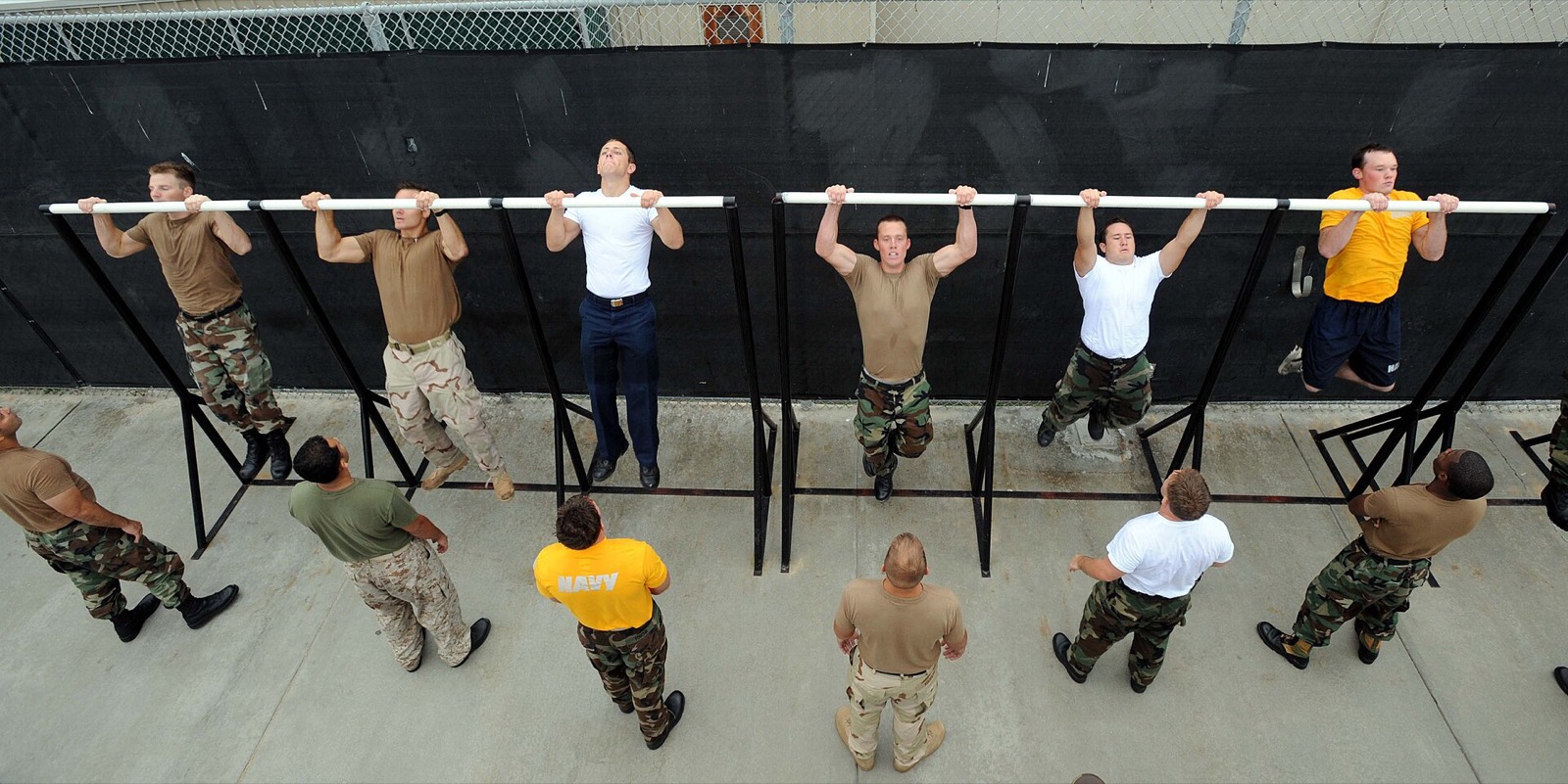 Des militaires font des tractions sur une rangée de barres pendant un test physique